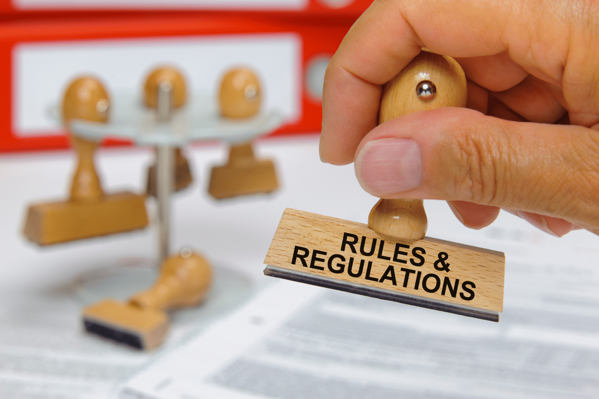 A hand holding a stamp that says Rules and regulations on it.