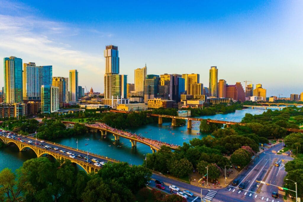Aerial drone view of Austin, Texas, showcasing the vibrant skyline at sunset. Modern towers illuminate the cityscape, highlighting its appeal for Austin real estate investment.