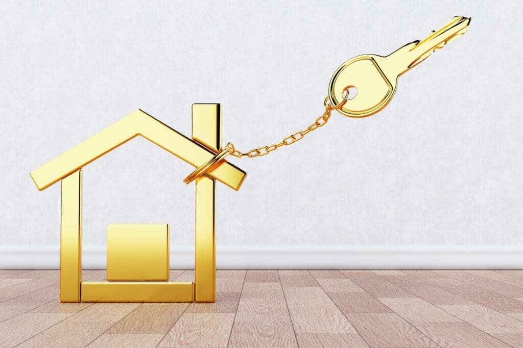 A golden key tied to a miniature golden house model symbolizes how following the Golden Rule of Real Estate Investing opens the door to success and profitability.