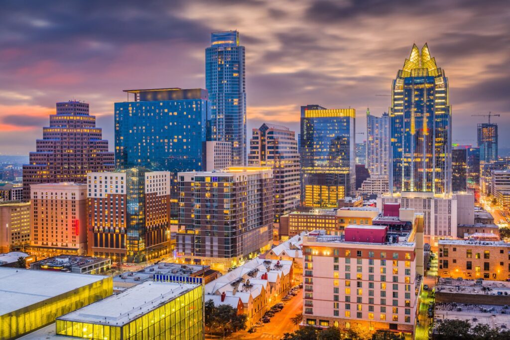 An urban skyline at dusk with illuminated skyscrapers and diverse architecture, representing the vibrant scene managed by a Property Manager in Austin TX.