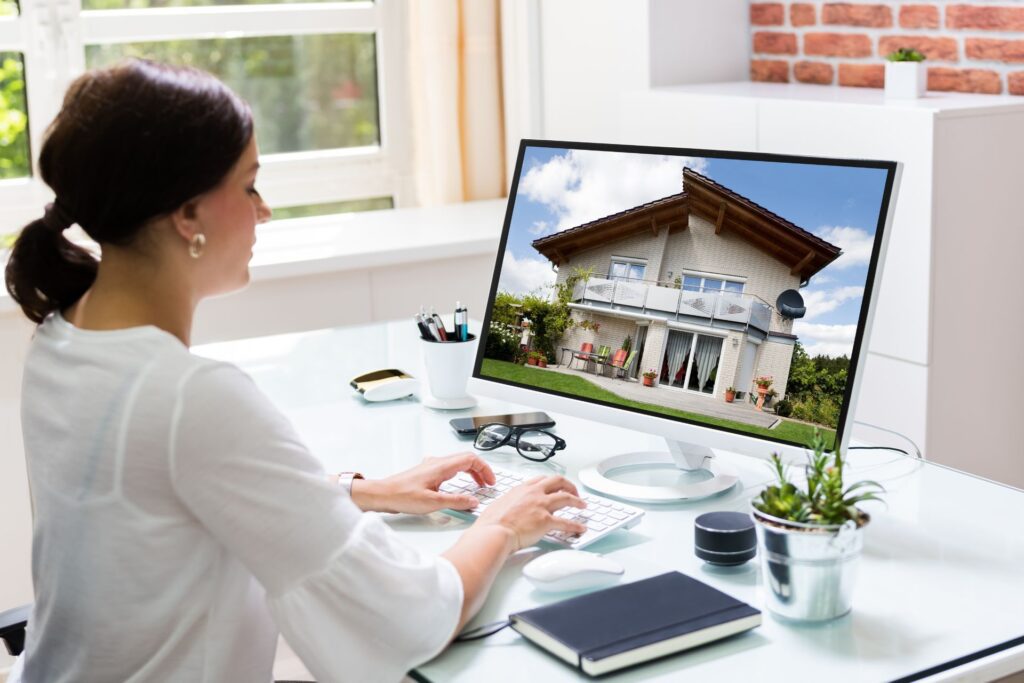 Woman managing rental property remotely on computer, viewing house listing on screen for out-of-state property management in Austin.