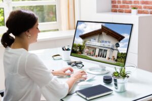Woman managing rental property remotely on computer, viewing house listing on screen for out-of-state property management in Austin.