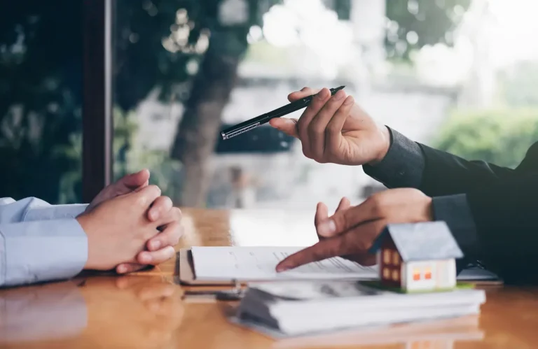 Homeowner reviewing rental property paperwork with a property management professional while deciding whether to sell or rent their house.
