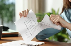 Close-up of a person tearing a lease document in half at a desk, representing breaking a lease in Texas.